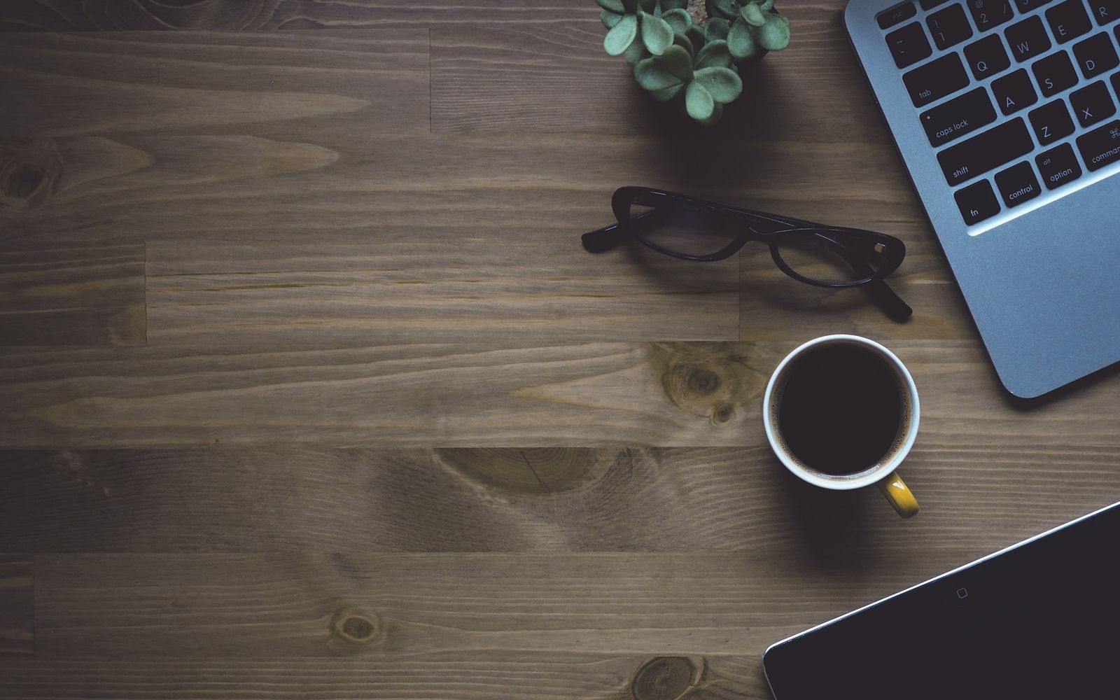 Bureau vu de dessus : ordinateur portable, lunettes et tasse de café
